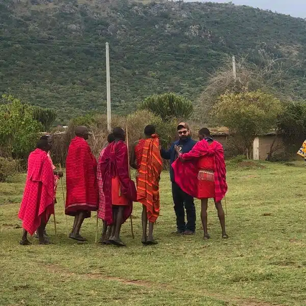 Safari guests interacting with Maasai community members during a cultural visit on an African safari in Kenya