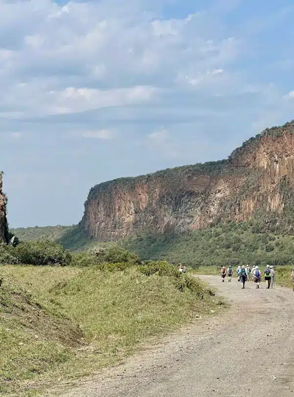 Travelers walking along the trails of Hell’s Gate National Park beneath towering cliffs