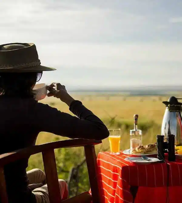 Traveler enjoying bush breakfast on an 8 Day Kenya Safari with views across the Masai Mara plains