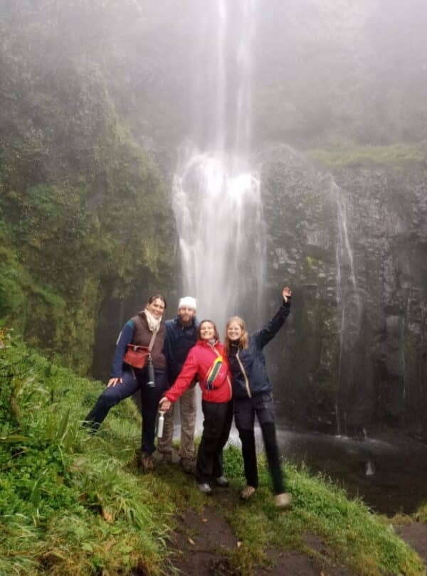 Hikers standing beside a waterfall on a forest trail