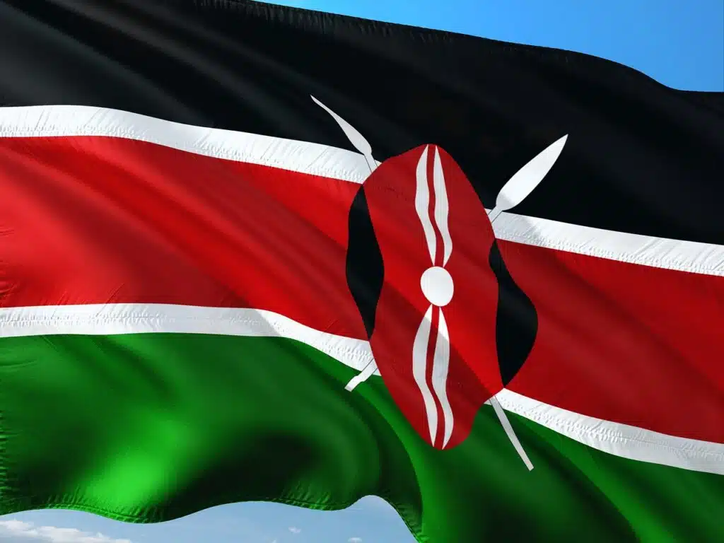 Kenyan flag waving against a blue sky, symbolizing national efforts in sustainability and the plastic ban