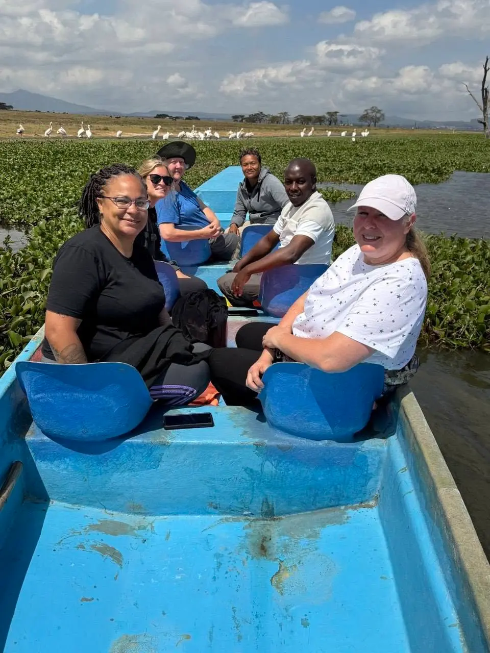 Guests enjoying a private boat safari on Lake Naivasha with pelicans and aquatic vegetation in the background