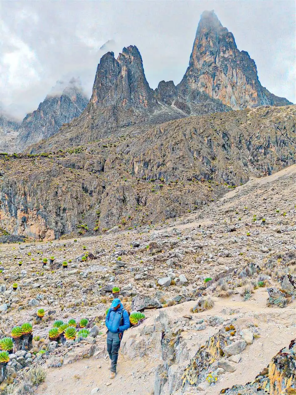 Hiker trekking below the rocky peaks of Mount Kenya