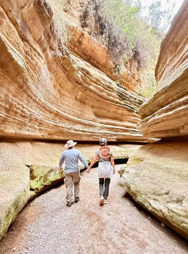 Travellers walking through a narrow sandstone gorge in Hell’s Gate National Park, Kenya.