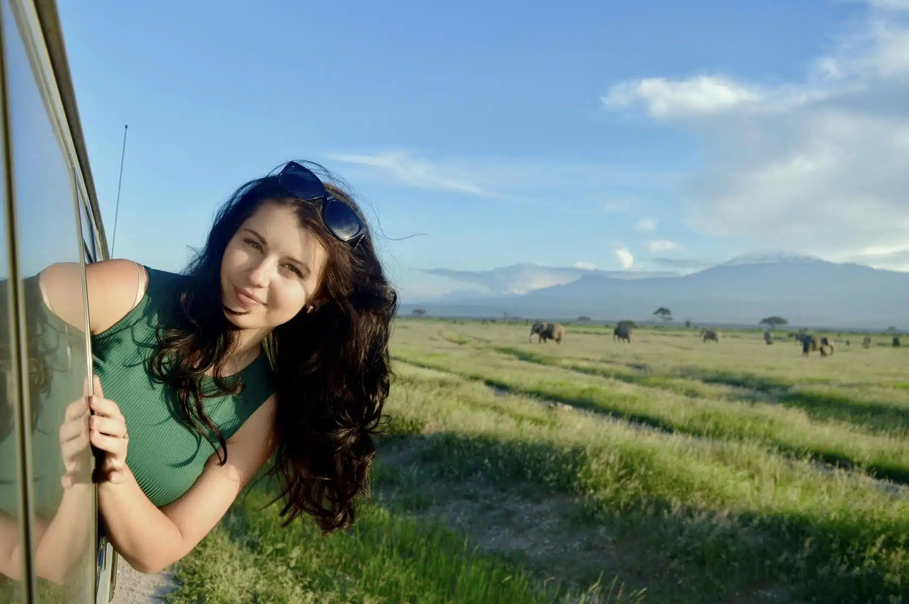 Traveler enjoying wide open grasslands and distant hills on a Kenya safari experience.