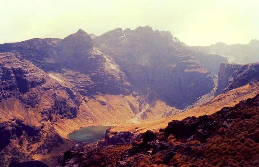 Scenic view of the rugged terrain in Sibiloi National Park, featuring towering mountains and a tranquil lake nestled in the valley.