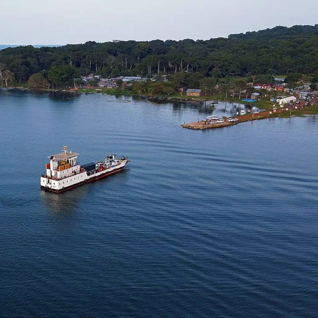 The ferry on its way to Kalangala Island, with the dock and surrounding greenery visible on the shore.