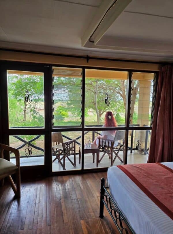 Guest relaxing on a private balcony overlooking the savannah at Ashnil Safari Lodge, Tsavo East