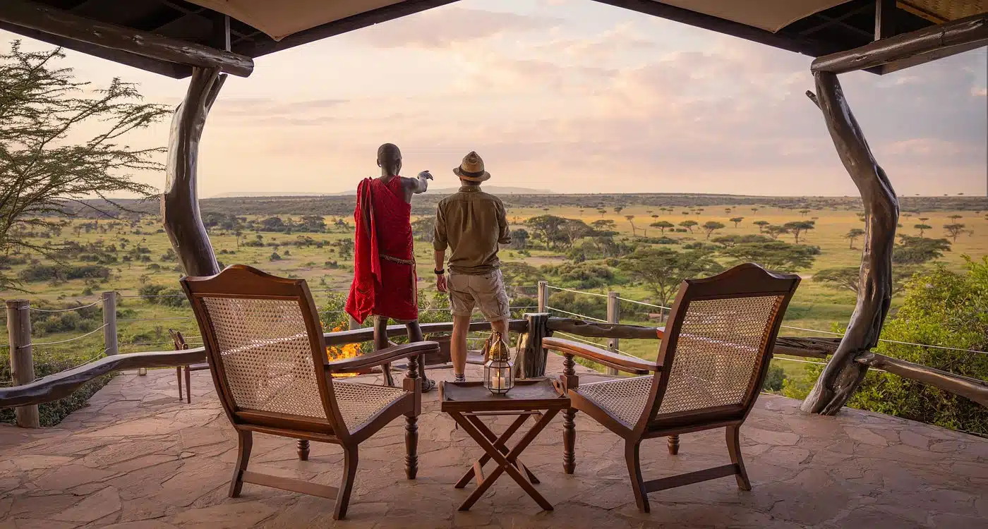 Gemfinders Safaris guest with Maasai guide overlooking the Masai Mara savannah at sunset