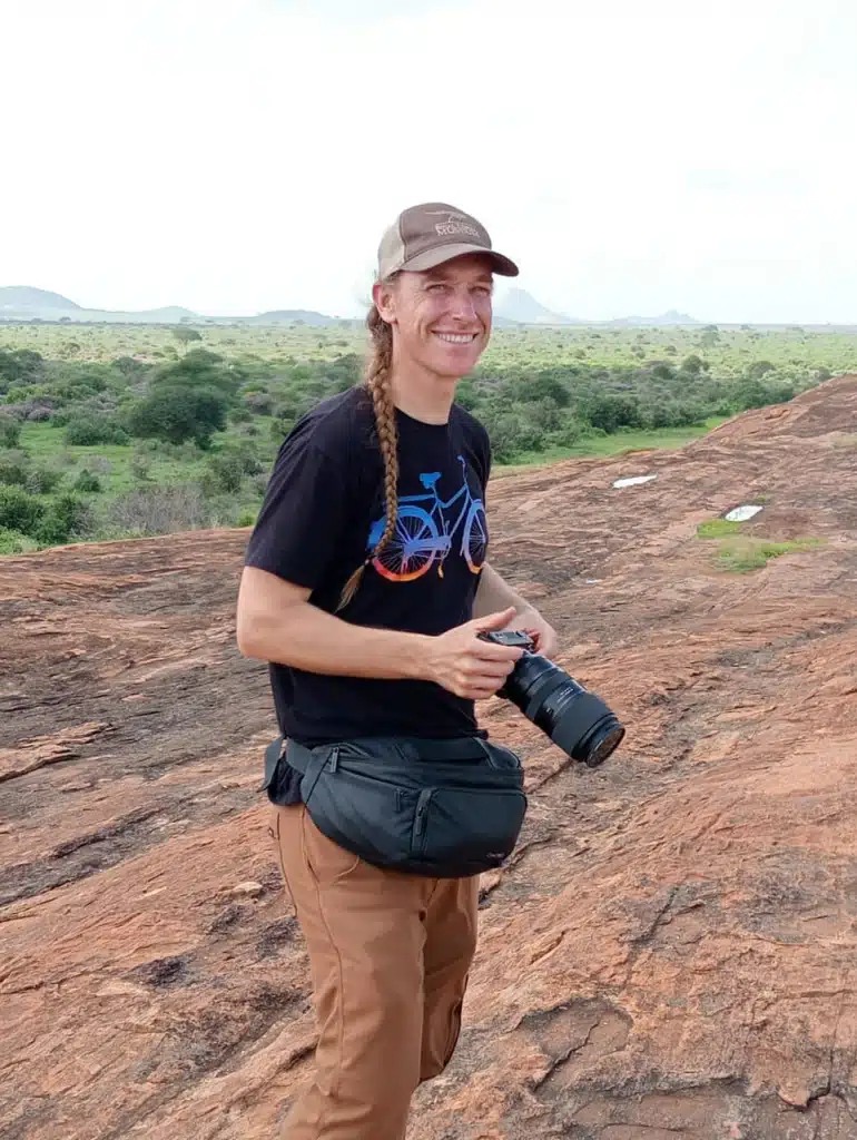 Safari guest equipped with a camera for photographing wildlife in a remote landscape