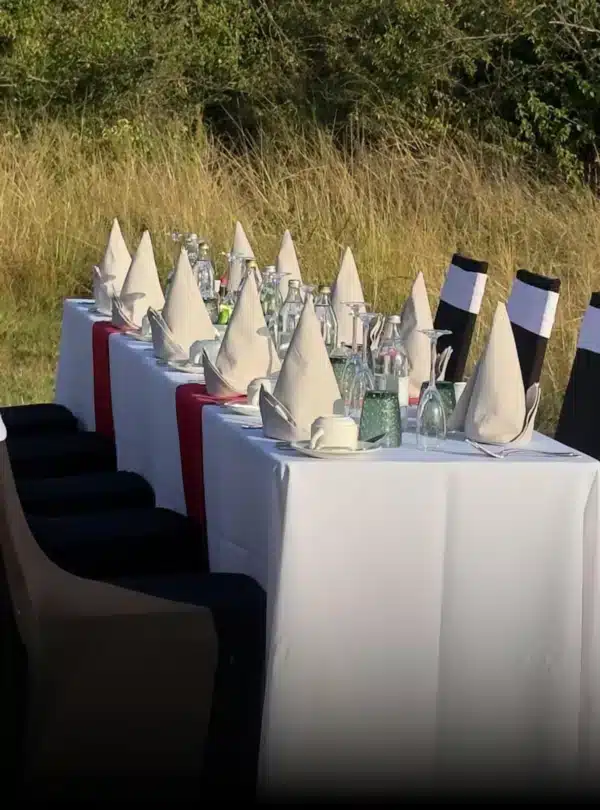 Luxury outdoor dining table with white linen, glassware, and folded napkins set in a natural bush setting during a Nairobi stopover tour.