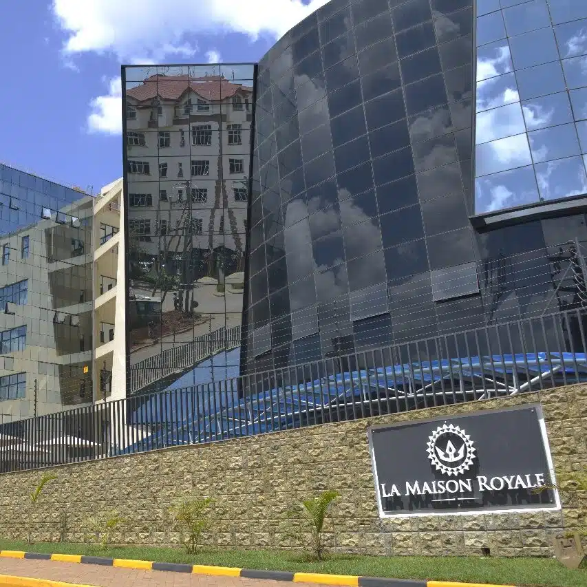 Exterior view of La Maison Royale Hotel Westlands, Nairobi — modern glass façade reflecting city buildings under a blue sky.