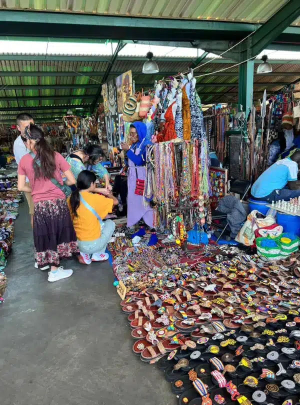 Travelers shopping for colorful beadwork, jewelry, and handcrafted sandals at the Maasai Market in Nairobi, Kenya.