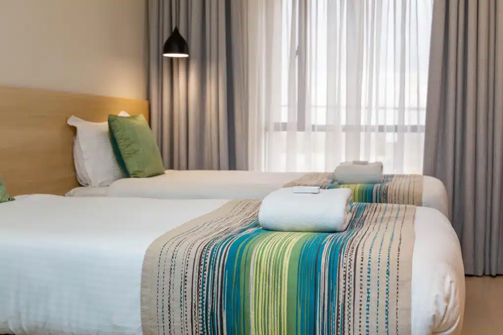Twin guest room at Kozi Suites Nairobi with modern décor and fresh towels prepared for guests.