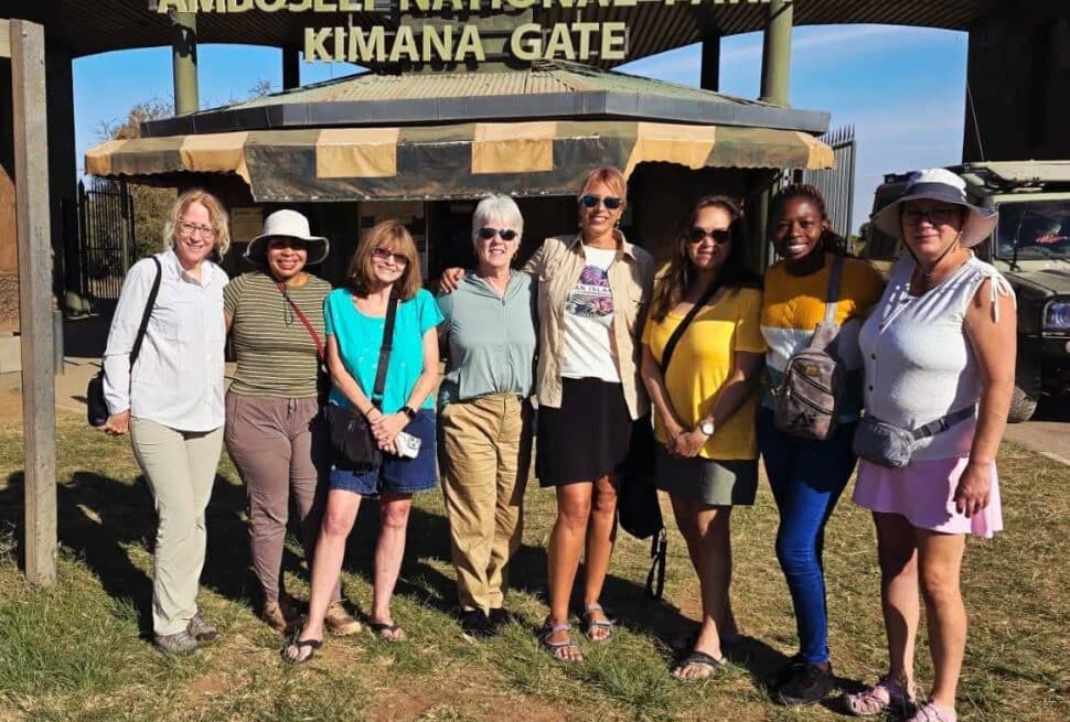 International safari guests pose together at the entrance to Amboseli National Park in Kenya before a game drive.