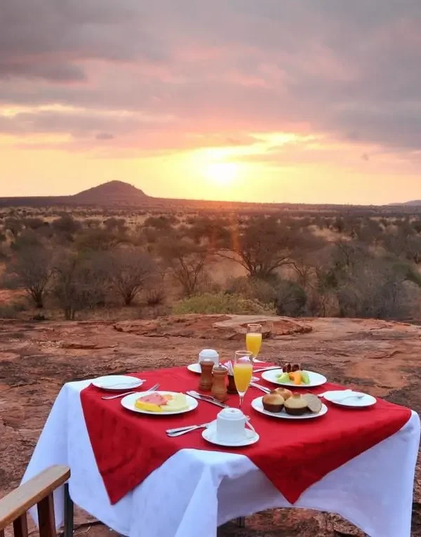Outdoor breakfast with wide Tsavo plains and hills at Kilaguni.