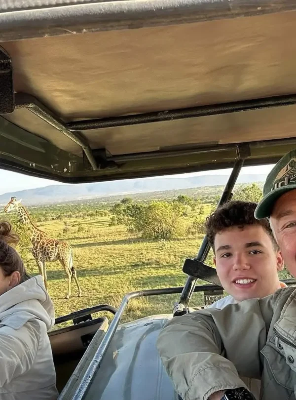 Guests on a 10-Day Kenya safari observing a giraffe from a private Land Cruiser.