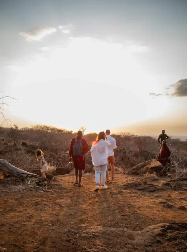 Guests on a guided nature walk with Maasai at sunset during a Kenya safari.