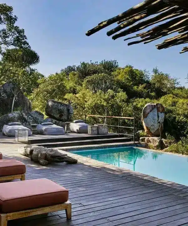 Masai Mara lodge pool deck surrounded by rocks and woodland on an 8-Day Kenya Tanzania Safari