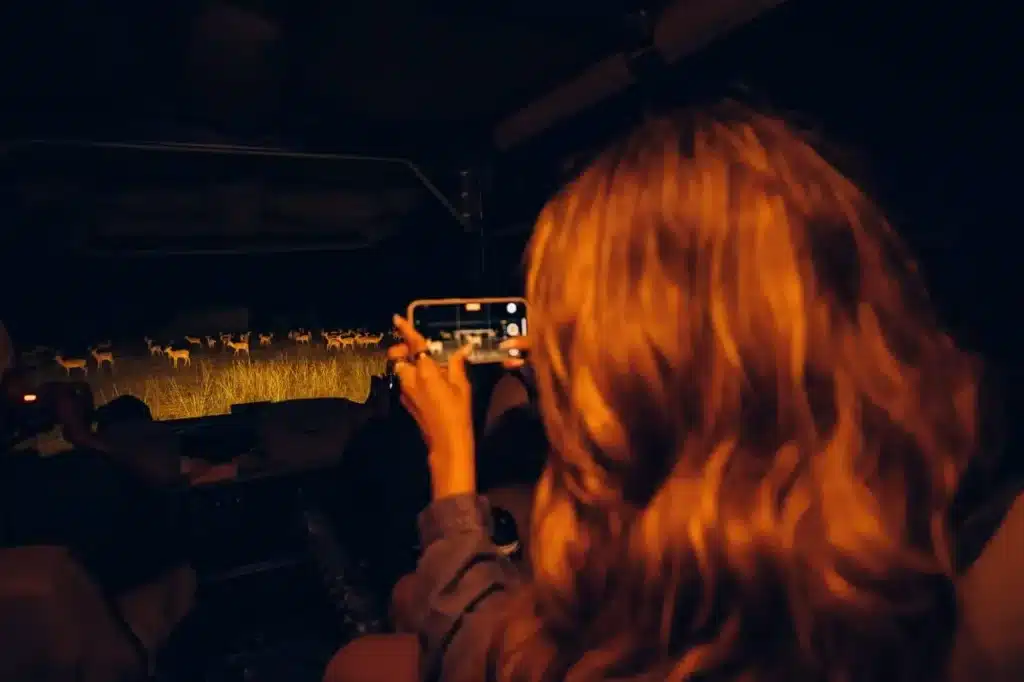 Guest taking photos during a night wildlife viewing on a private 6-day Masai Mara safari in Kenya.