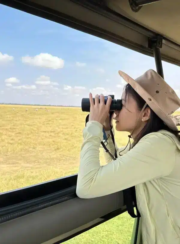 Safari guest using binoculars to view wildlife in Amboseli