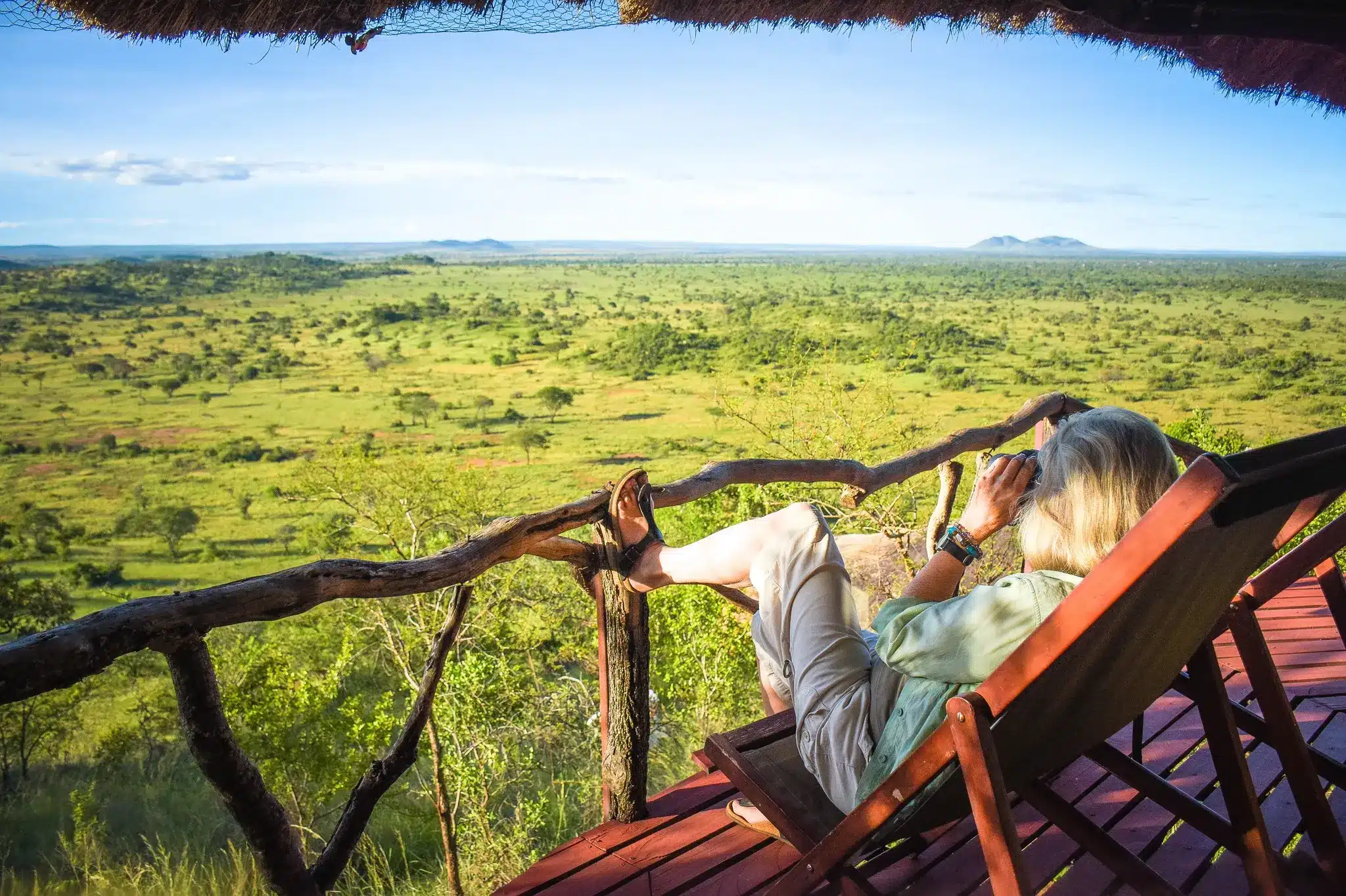 traveller relaxing on lodge deck overlooking kenya savannah during 3 to 5 day safari